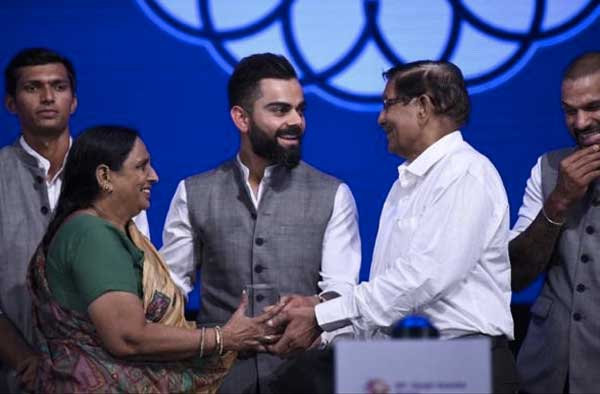 Lalita Sharma's parents receiving award from Virat Kohli
