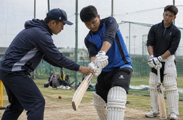 Cricket coach teaching players 